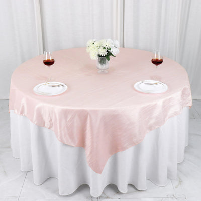 Round pink tablecloth draped elegantly over a white table setting with wine glasses.