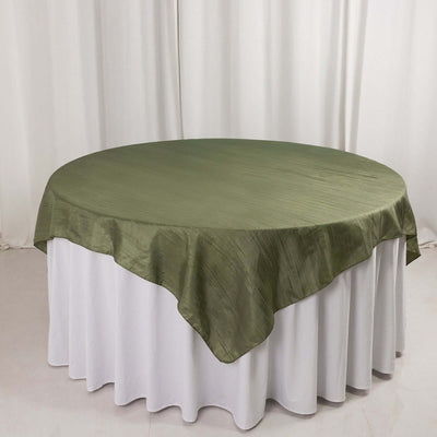 Round olive green tablecloth draped over a white table.