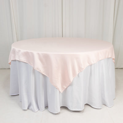 Round table with a pink satin tablecloth on a white skirt.