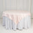 Round table with a pink satin tablecloth on a white skirt.