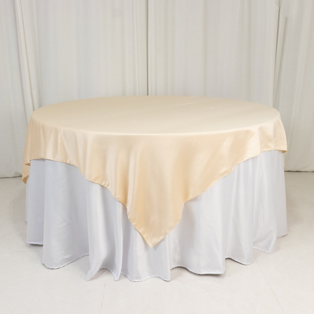 Round table with beige satin tablecloth and white skirt