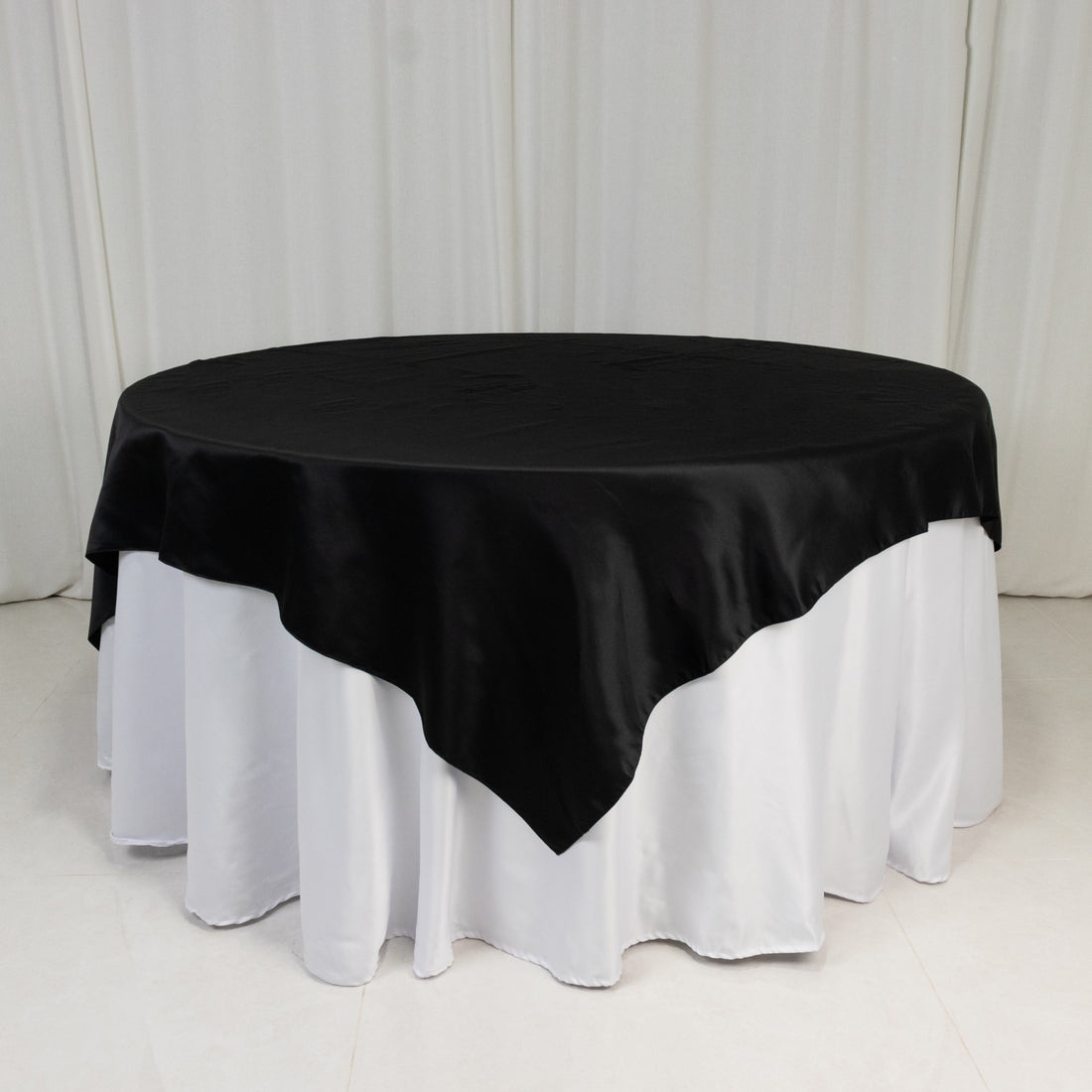 Black satin tablecloth draped over a white table