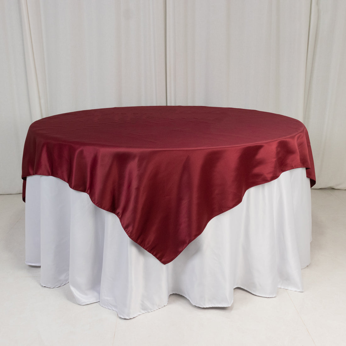 Round burgundy tablecloth draped elegantly over a white table