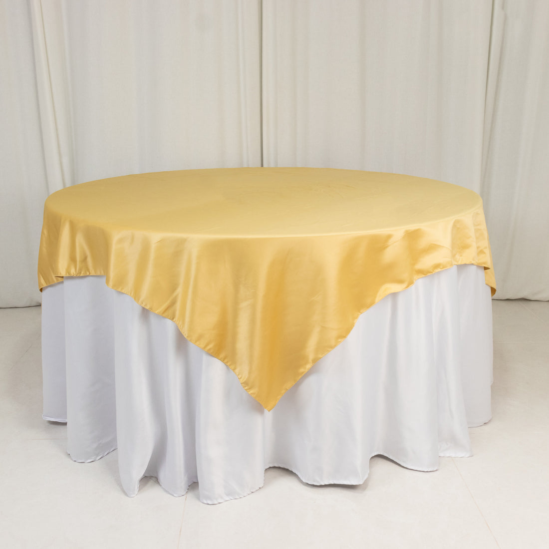 Round table with a yellow satin tablecloth and white skirt