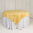 Round table with a yellow satin tablecloth and white skirt