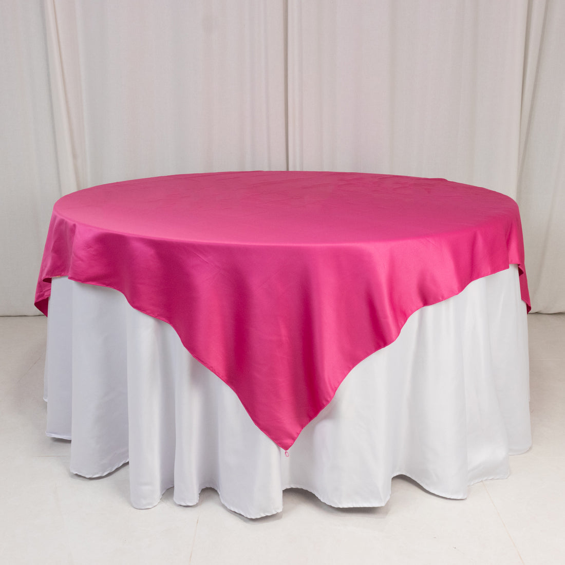 Round table with a pink satin tablecloth and white skirt.