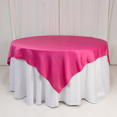 Round table with a pink satin tablecloth and white skirt.