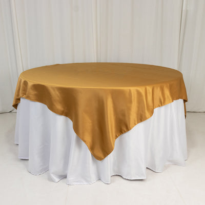 Round gold satin tablecloth on a white table.