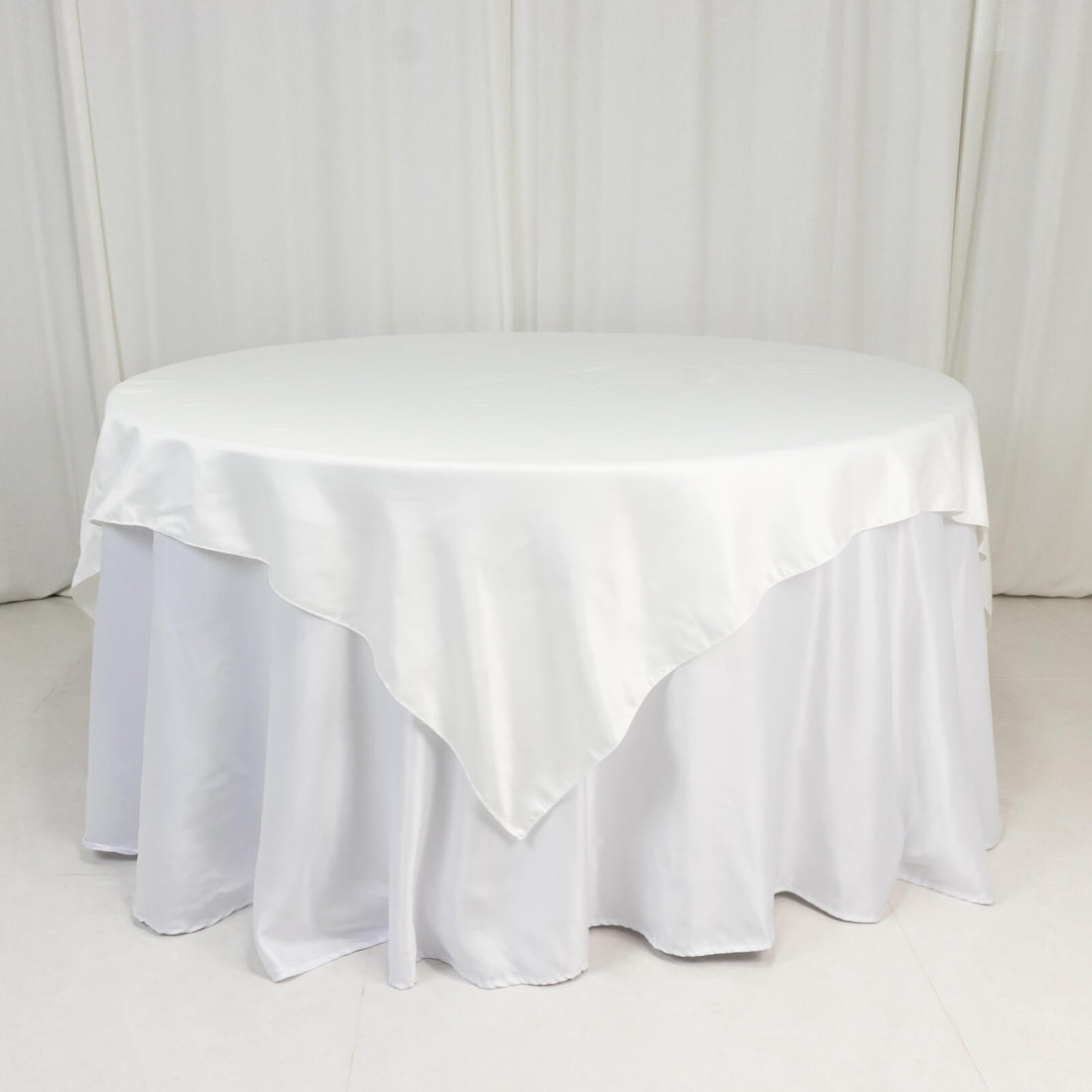 White round table with a smooth tablecloth draping to the floor.
