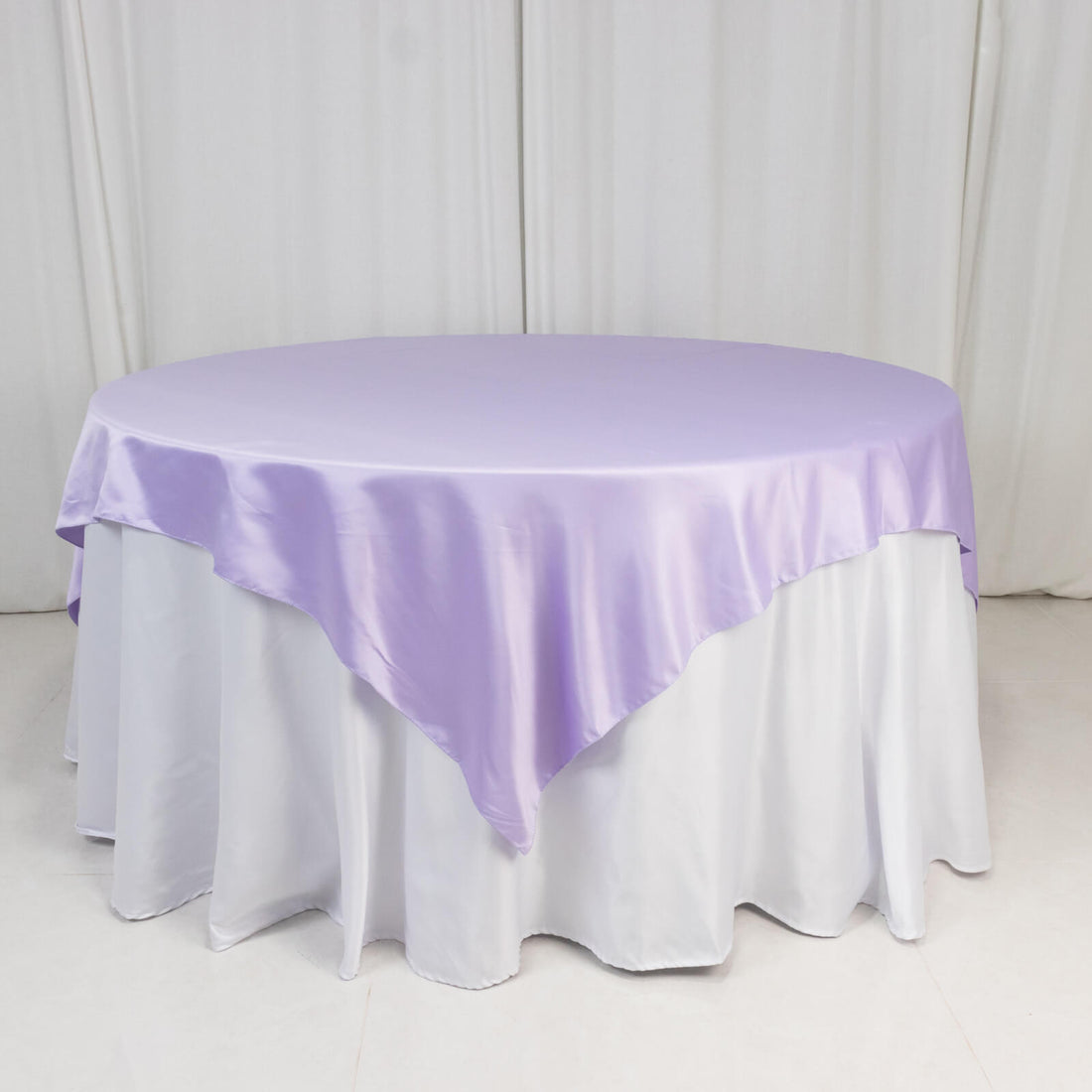 Round table covered with a lilac satin tablecloth.