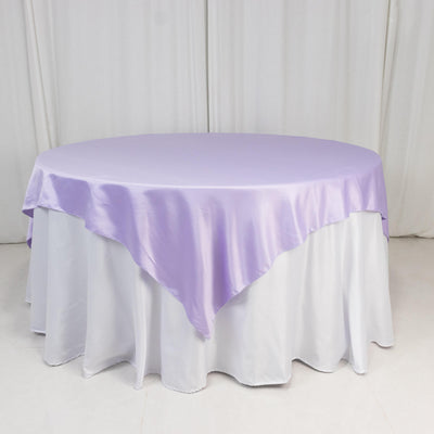 Round table covered with a lilac satin tablecloth.