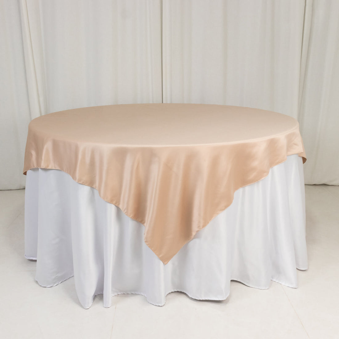 Round table with beige satin tablecloth and white skirt