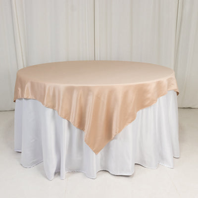 Round table with beige satin tablecloth and white skirt