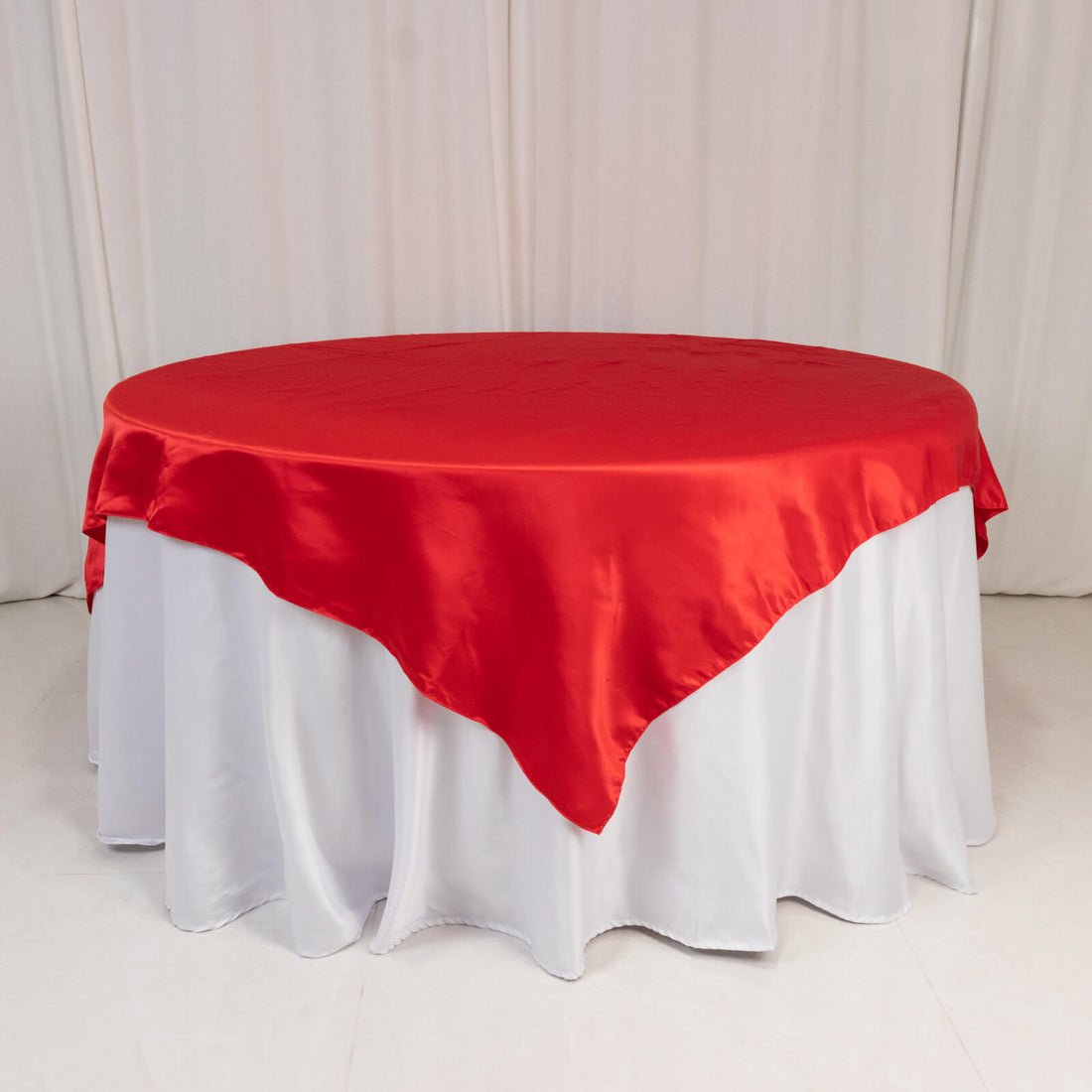 Round table with red satin tablecloth and white skirt