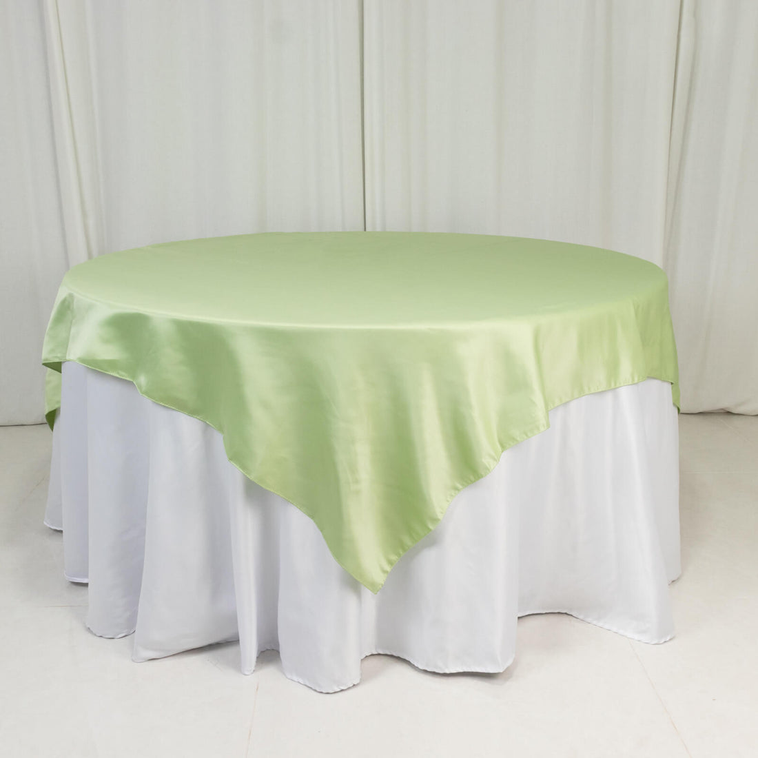 Green satin tablecloth draped over a round table.