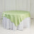 Green satin tablecloth draped over a round table.