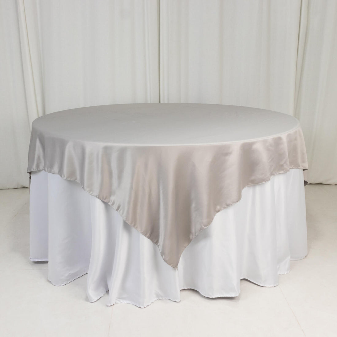 Round table with a beige satin tablecloth draped elegantly.