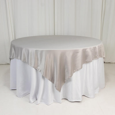 Round table with a beige satin tablecloth draped elegantly.