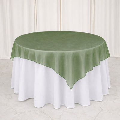 Green sheer overlay round tablecloth on white table at elegant event setup