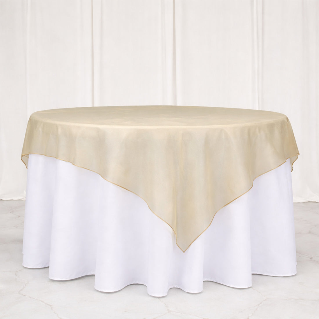 Elegant round tablecloth with a gold satin overlay on a white table.