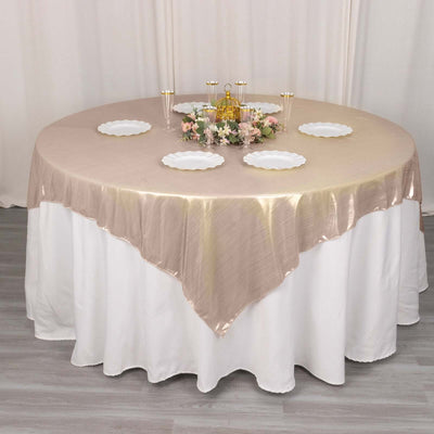 Elegant round table setting with gold satin tablecloth and decorative plates.
