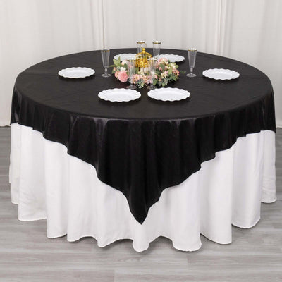 Black and white round tablecloth on a dining table with decorative plates and flowers.