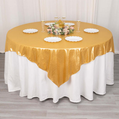 Gold tablecloth draped elegantly over a round table with decorative plates and centerpiece.