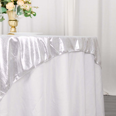 Elegant silver tablecloth draping over a white table with floral centerpiece.
