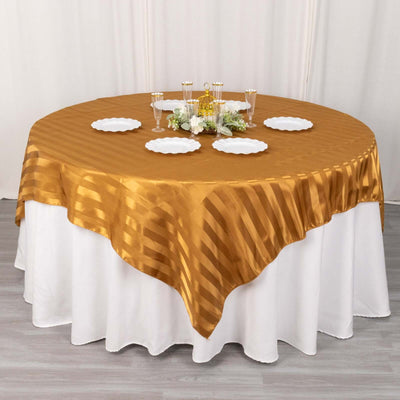 Round gold tablecloth draped over a white table with plates and decorations.