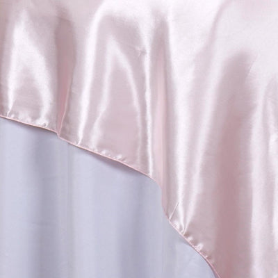Light pink satin table runner draped elegantly over a white table.
