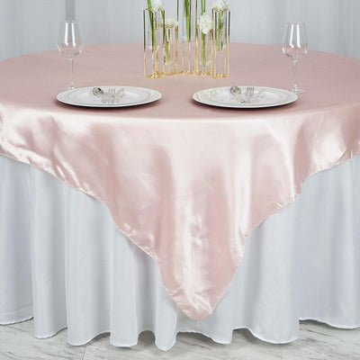 Pink satin tablecloth draped elegantly over a white table with plates and glasses.