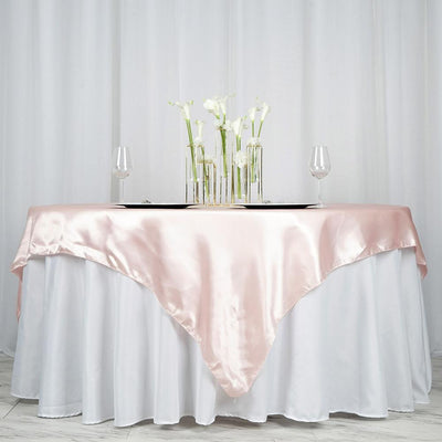 Elegant pink satin tablecloth draped over a white table with floral centerpieces.