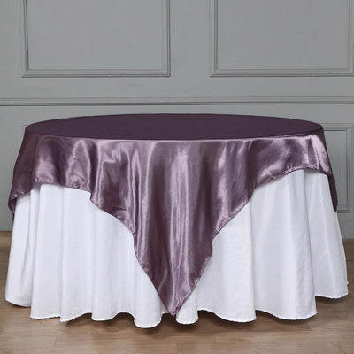 Purple satin tablecloth draped over a round white table.