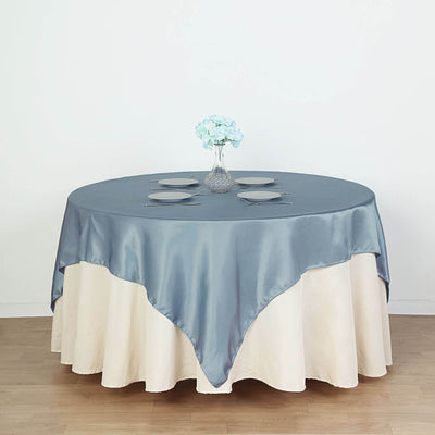 Elegant round table with blue satin tablecloth and floral centerpiece.