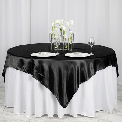 Elegant black satin tablecloth draped over a round table with floral centerpiece.