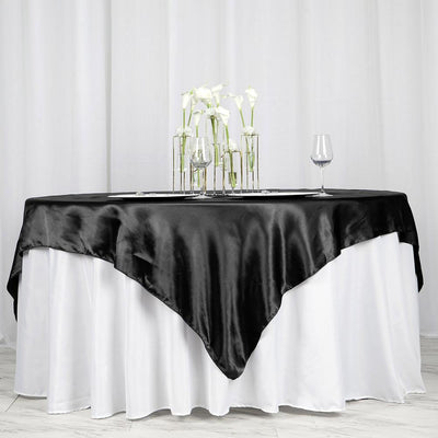 Black satin table overlay on a white tablecloth with glassware and flowers.