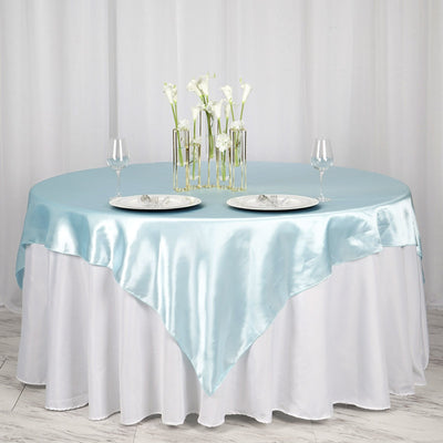 Elegant round table set with blue satin tablecloth and floral centerpiece.