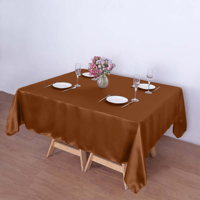 Brown tablecloth draped over a wooden table set with dishes and flowers.