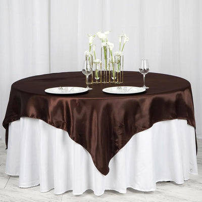 Elegant round table set with brown satin tablecloth and white plates