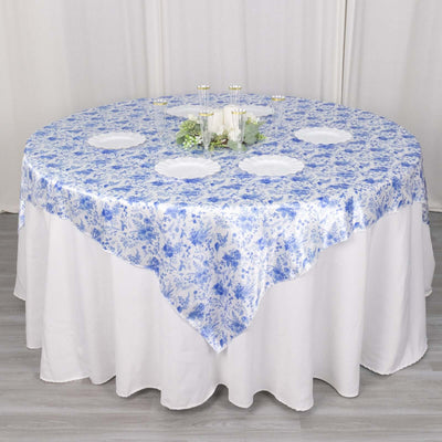 Round blue floral tablecloth on a white table with decorative accents.