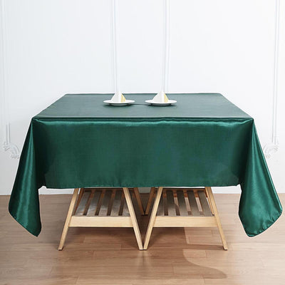 Green tablecloth draped over a wooden table with candles and holders.