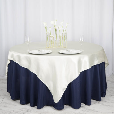 Round table with a cream and navy tablecloth, set with plates and glasses.