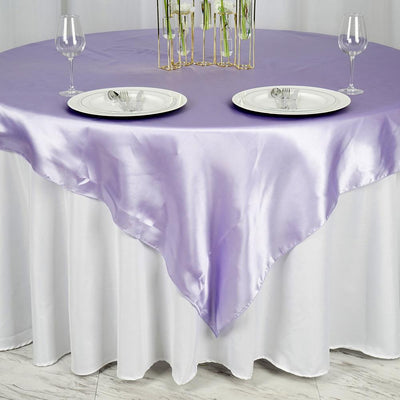 Purple satin table overlay with plates and glasses on a white tablecloth.