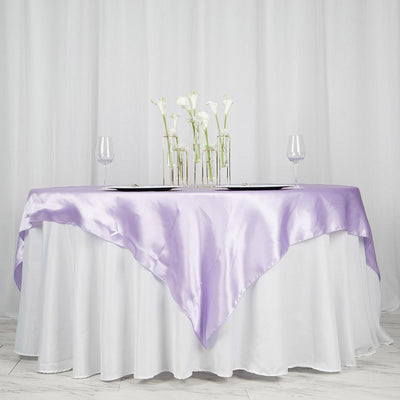 Purple satin tablecloth draped over a round table with decorative vases and glasses.