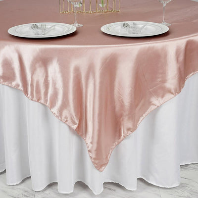 Rose satin tablecloth draping elegantly over a white table with plates and cutlery.