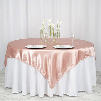 Elegant round table with pink satin tablecloth and floral centerpiece.