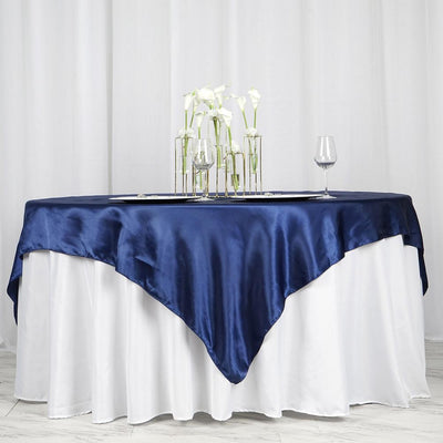 Navy satin tablecloth draping elegantly over a white table, adorned with flowers and glassware.