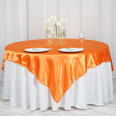 Orange satin tablecloth draped over a round table set for dining.