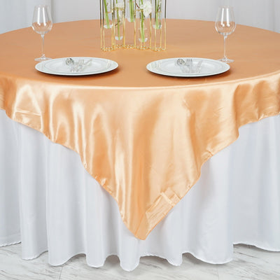 Peach satin tablecloth draped over a round table set for dining.