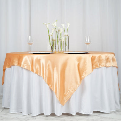 Elegant table setting with an orange satin tablecloth and floral centerpiece.